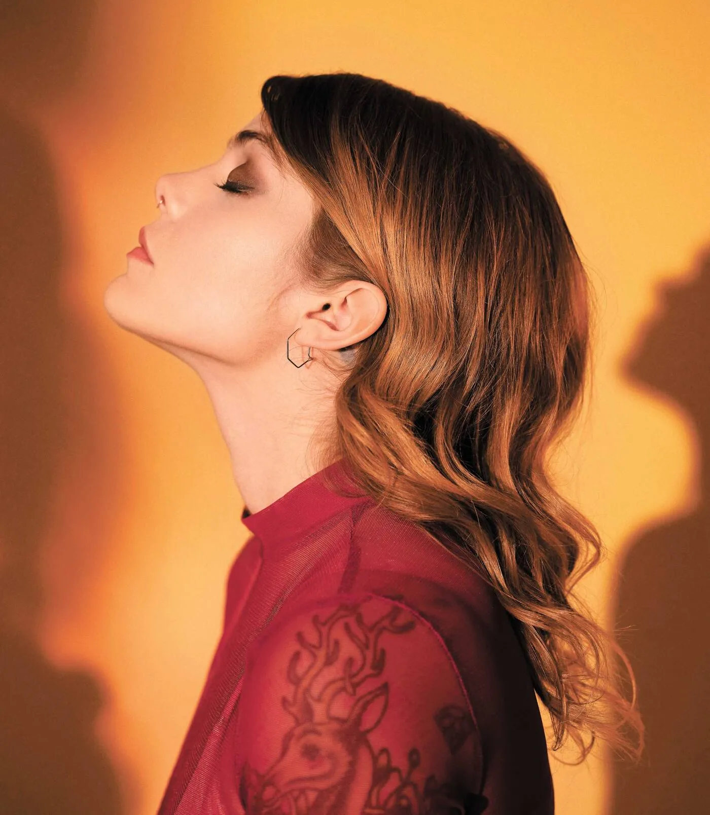Coeur de Pirate in profile with her eyes closed and head tilted back against warm amber light