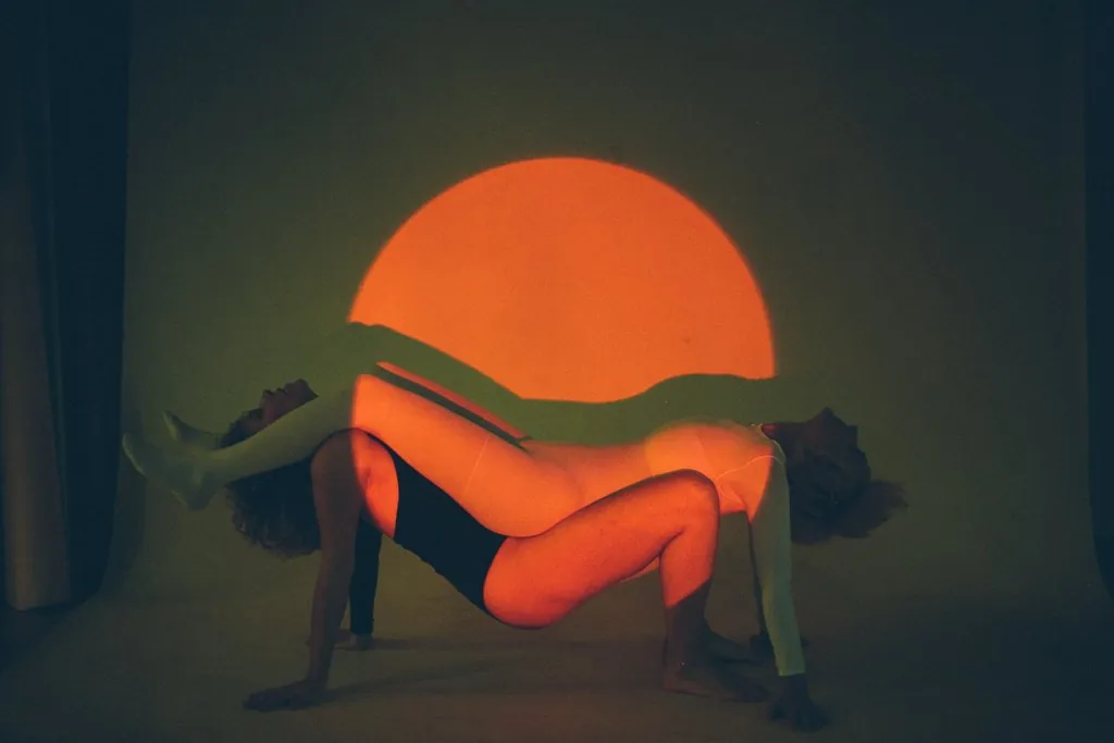 A woman arching backwards in front of a projected orange circle