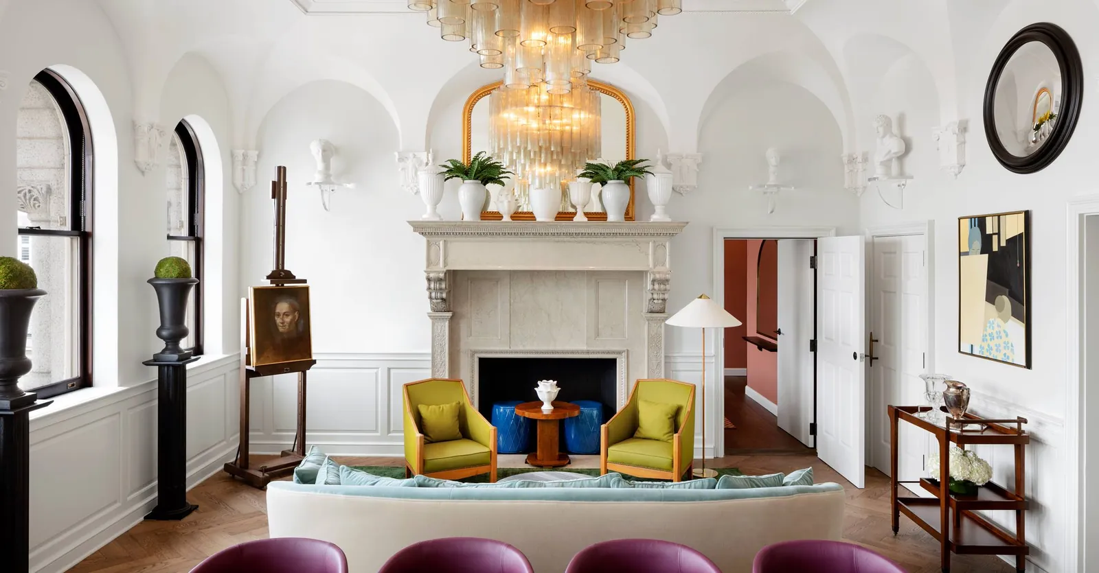 A suite living room with a marble fireplace, a glass chandelier and a vaulted white ceiling